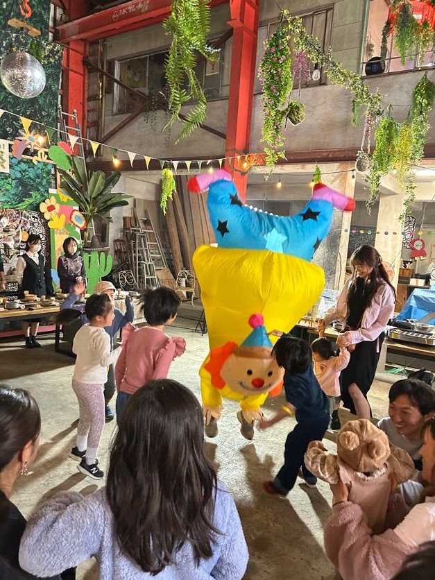 大きな着ぐるみのキャラクターと屋内で踊る子どもたち。