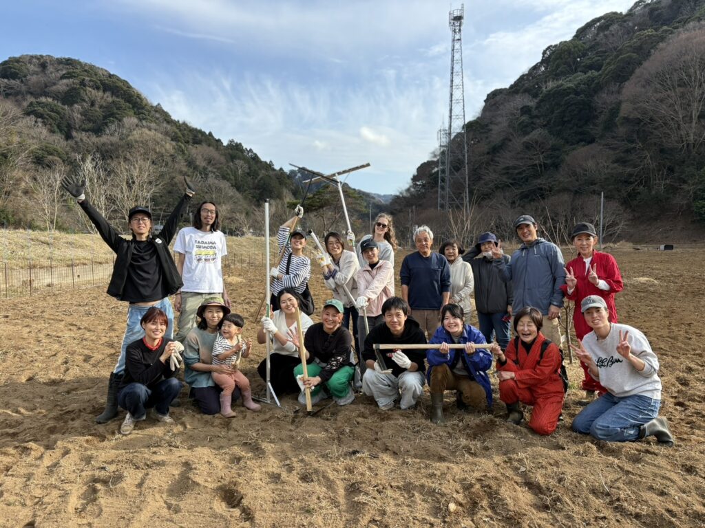 Participants gathered with farm tools, smiling, at the IZU DAO Farm.